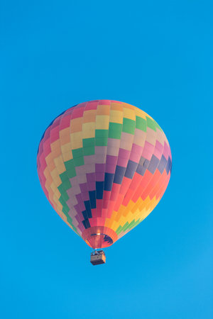 Colorful hot air balloon flying in the bright blue skyの写真素材