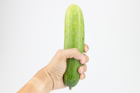 Hand holding fresh cucumber isolated on white background, clipping path includedの写真素材