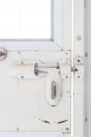 Old white metel window with padlock. Close-up. White background.の写真素材