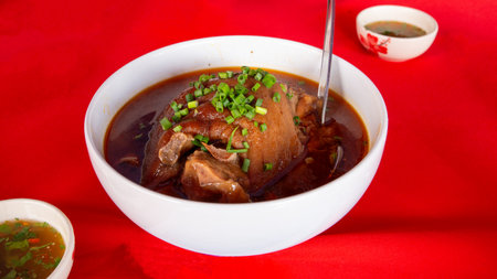Chinese Yunnan style stewed pork in a white bowl on a red backgroundの写真素材