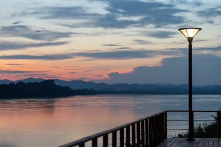 Calm evening light reflects off the lake as the sun sets over the serene water and clouds on the horizonの写真素材