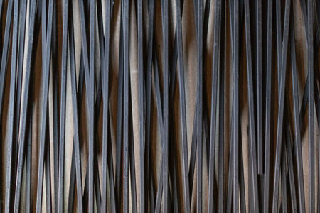 Close-up macro of a brown bamboo mat and steel wire fence with contrasting textures and patternsの写真素材