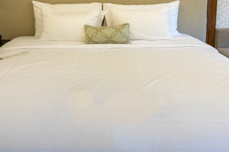 A luxury hotel room's comfortable double bed with crisp white bedding, plump pillows, and a stylish...