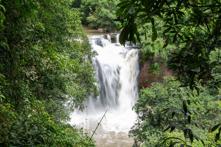 A stunning natural waterfall cascades down rocks in a lush green forest landscape