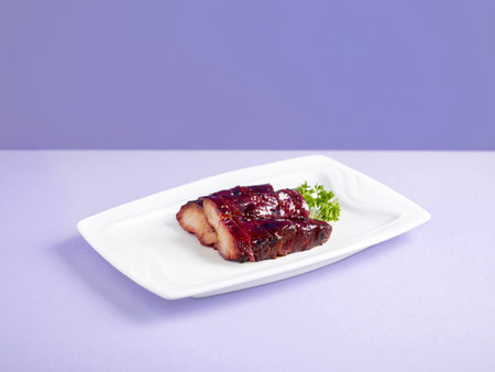 Charred BBQ Pork with Honey Sauce Served in a dish isolated on wooden board side view on grey backgroundの写真素材