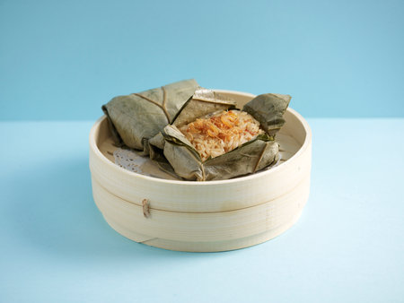 Steamed Glutinous Rice with Chicken Wrapped in Lotus Leaf served in a wooden bowl with chopsticks isolated on mat side view on grey marble backgroundの写真素材