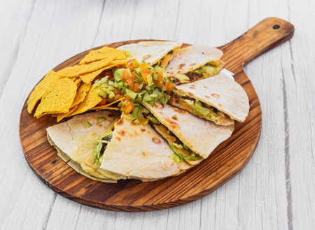 Pizza dillas and nachos served in cutting board isolated on grey wooden background side view of fastfoodの写真素材