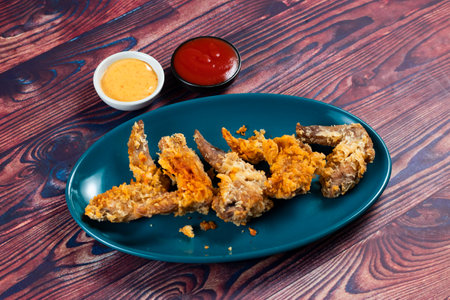 Crispy chicken wings with tomato sauce and mayo dip isolated on cutting board side view of fastfoodの写真素材