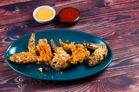 Crispy chicken wings with tomato sauce and mayo dip isolated on cutting board side view of fastfoodの写真素材