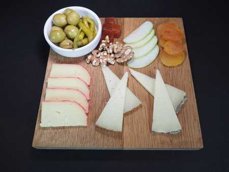 Assorted cheese platter served in a wooden board isolated on dark background top viewの写真素材