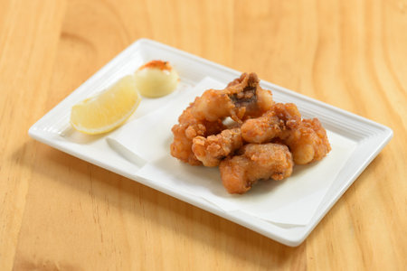 japanese food fried Tako Karaage with lemon in a white dish isolated on wooden table top viewの写真素材