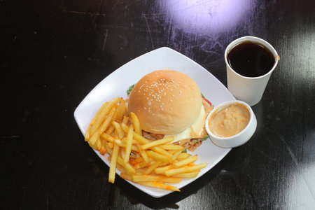 Chicken cheese burger with fries, mayo dip and soda drink served in a dish isolated on dark background side view of indian spicy fastfoodの写真素材