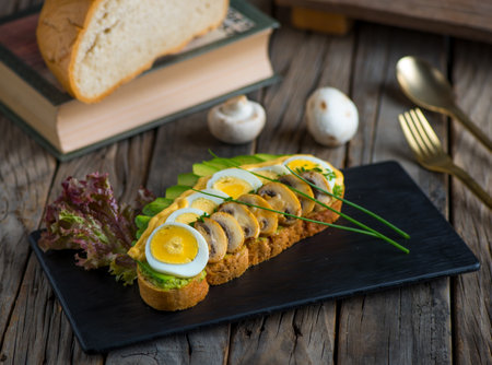 avocado toast with mushroom and egg isolated on cutting board side view of breakfast on wooden backgroundの写真素材