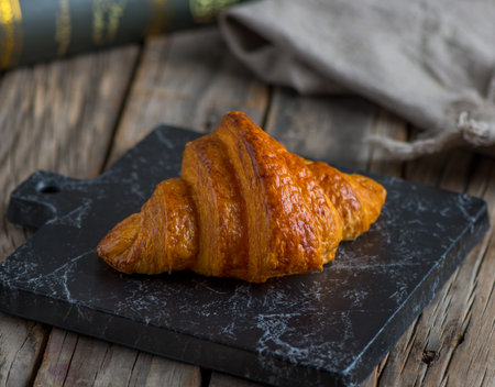 chocolate croissant served in a dish isolated on cutting board side view of breakfast on wooden backgroundの写真素材
