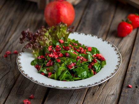 rocca salad with strawberry and pomegranate sauce served in a dish isolated on wooden background side viewの写真素材