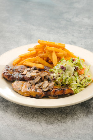 Specialty Grilled Pork Chop with salad and french fries served in a dish isolated on background side view of fastfoodの写真素材