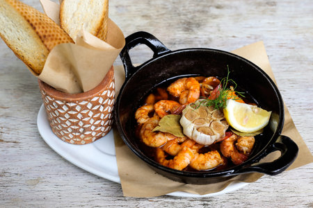 Sizzling Gambas Al Pil Pil with garlic bread served in a dish isolated on grey background side view of snacksの写真素材