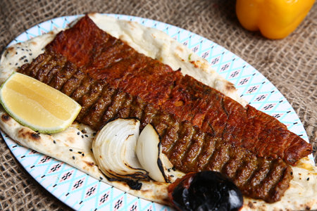 Grilled fish with onion and lemon on a plate on a burlap backgroundの写真素材