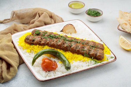 Chelo or Chelow Kabab with rice, tomato and lime served in dish isolated on table top view of...