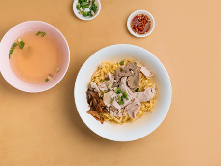 Minced meat Noodle in a bowl with soup, chili sauce and spring onion top view on wooden tableの写真素材