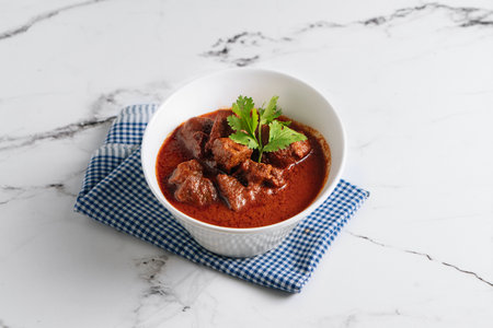 Mutton Rogan Josh, mutten qorma, mutten curry, mutton karahi in a dish isolated on napkin side view on grey backgroundの写真素材