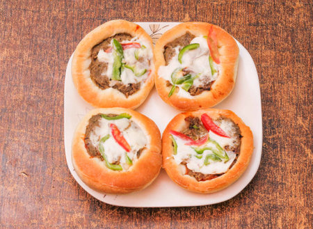 Bread stuffed with minced meat and vegetables on a wooden background.