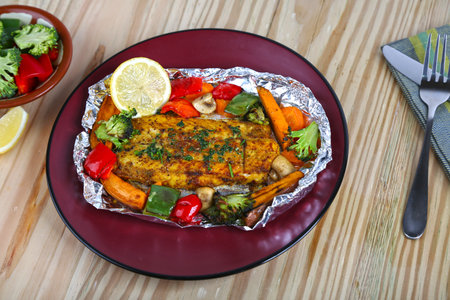 Steam Baked Hammour With Vegetables with lime served in dish isolated on table side view of middle east foodの写真素材