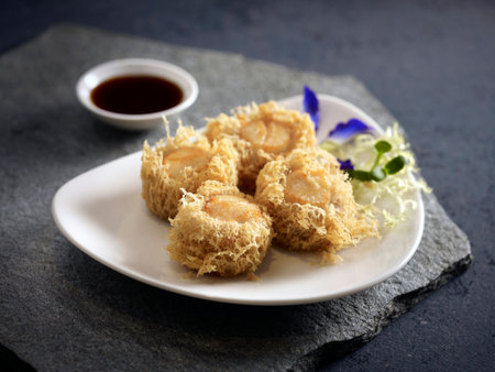 Crispy fried Yam Ring stuffed with Scallop served in a dish isolated on wooden board side view dark backgroundの写真素材