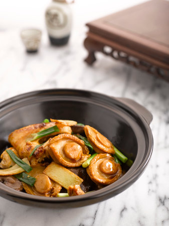 Braised Chicken and Abalone with Abalone Sauce served in Casserole served in a pot side view on grey backgroundの写真素材