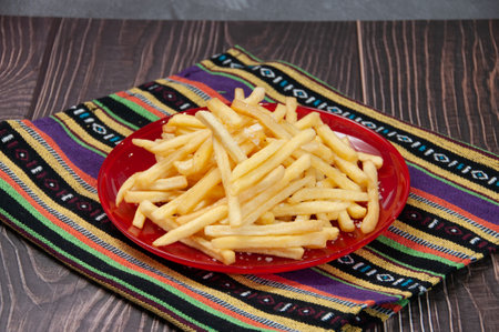 Plain Fries served in a dish isolated on napkin side view on dark background