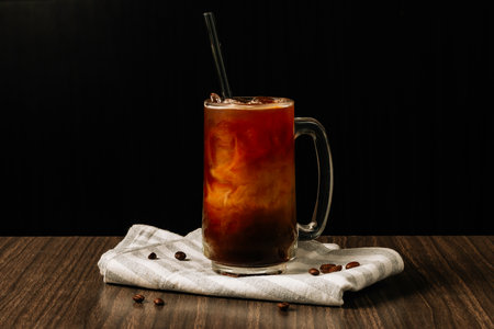 Iced coffee in a tall glass and coffee beans, dark concrete table Cold summer drink over dark wooden...