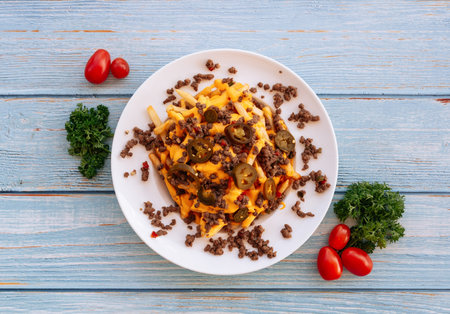Tasty beef fries and tomatoes served in white plate on wooden table top view