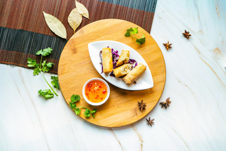 Fried Spring Rolls with chilli sauce served in dish isolated on wooden board top view on marble...