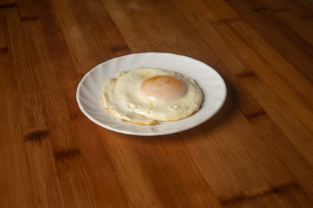 Sunny side up egg fry omelette poached served in plate isolated on wooden table top view of indian...