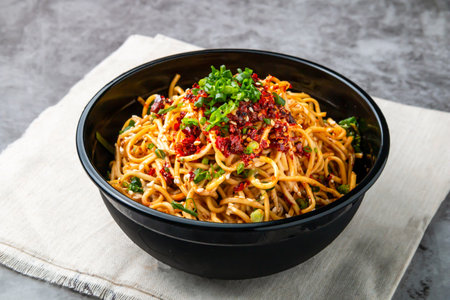 Bashu cold noodles topping with chilli paste, spring onion and sesame seeds served in bowl isolated on wooden table side view of hong kong fast foodの写真素材