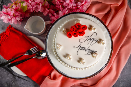Happy anniversary White Pearl Cake or women day and valentine celebration with flowers, spoon and fork served on board isolated on napkin side view of cafe bake foodの写真素材