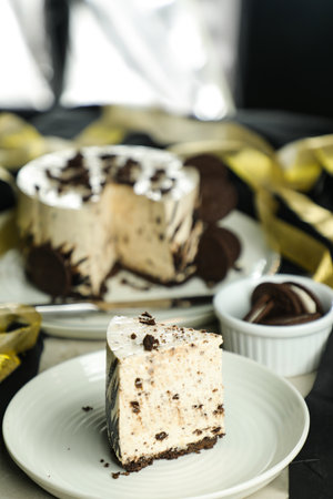Oreo Cheesecake slice include chocolate, cream, sugar with fork and flowers served in plate isolated on napkin side view of cafe foodの写真素材