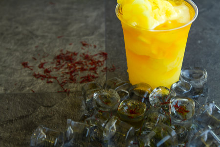 Saffron smoothie with ice cube served in disposable glass isolated on table side view of healthy morning smoothie drinkの写真素材