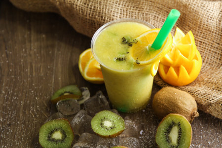 Orange and Kiwi cocktail juice served in disposable glass isolated on table side view of healthy drinkの写真素材