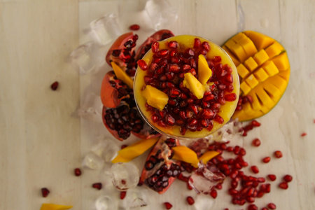 Mango juice and pomegranate seeds served in disposable glass isolated on table top view of healthy drinkの写真素材