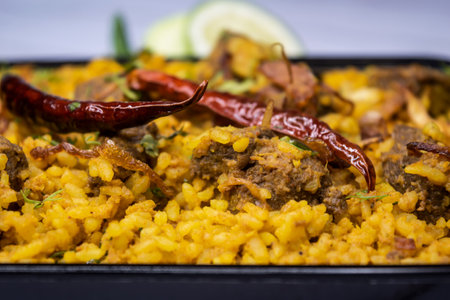 Achari beef khichuri biryani rice pulao with cucumber and lemon slice served in dish isolated on wooden table closeup side view of bangladeshi and indian spices foodの写真素材