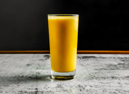 mango lassi or milk shake with yogurt, sugar, water and ice served in glass side view on grey background drinkの写真素材