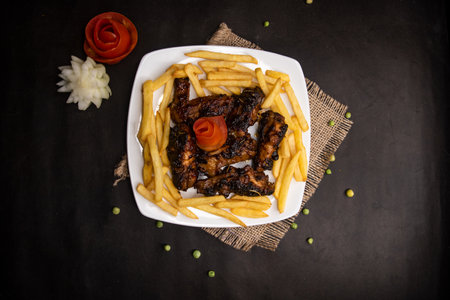 chicken bbq wings with fries served in dish isolated on napkin mat top view of fastfood foodの写真素材