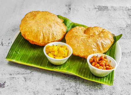 poori set or puri with chnnay and veg curry with chutney, raita and sauce served in dish isolated on banana leaf top view of indian and singapore spicy foodの写真素材