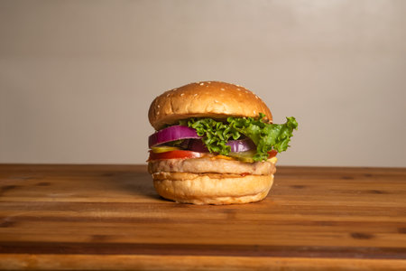 Classic Chicken Cheese Burger with Bacon isolated on wooden table top view of french unhealthy junk fastfoodの写真素材