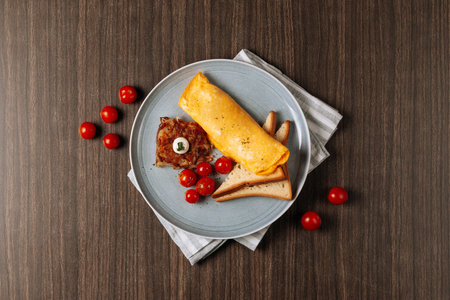 Omelette with bread toast and tomato isolated on wooden table top viewの写真素材