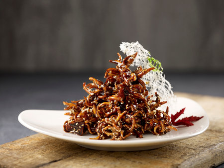 Crispy fried Baby Squid served in a dish isolated on wooden board side view dark backgroundの写真素材