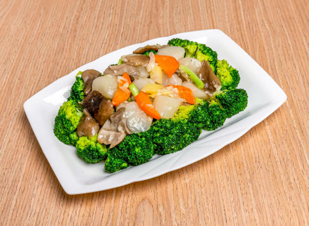 Stir fried Scallops with Greens including broccoli, tomato and scallions served in tray dish isolated on wooden table side view of hong kong foodの写真素材