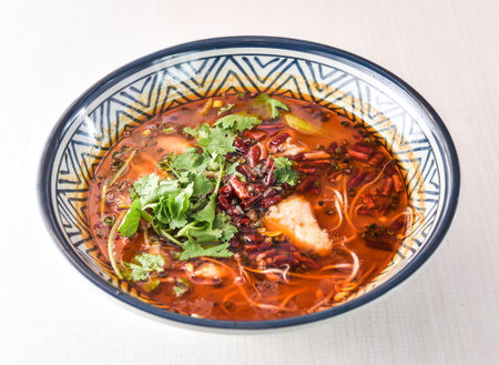 Sichuan Boiled fish with red chilli, noodles, green onion, potato powder and coriander served in bowl isolated on white background side view of hong kong foodの写真素材