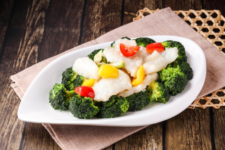 Sauteed Broccoli Balls with steamed fish, tomato and green onion served in dish isolated napkin side view of hong kong food on wooden backgroundの写真素材
